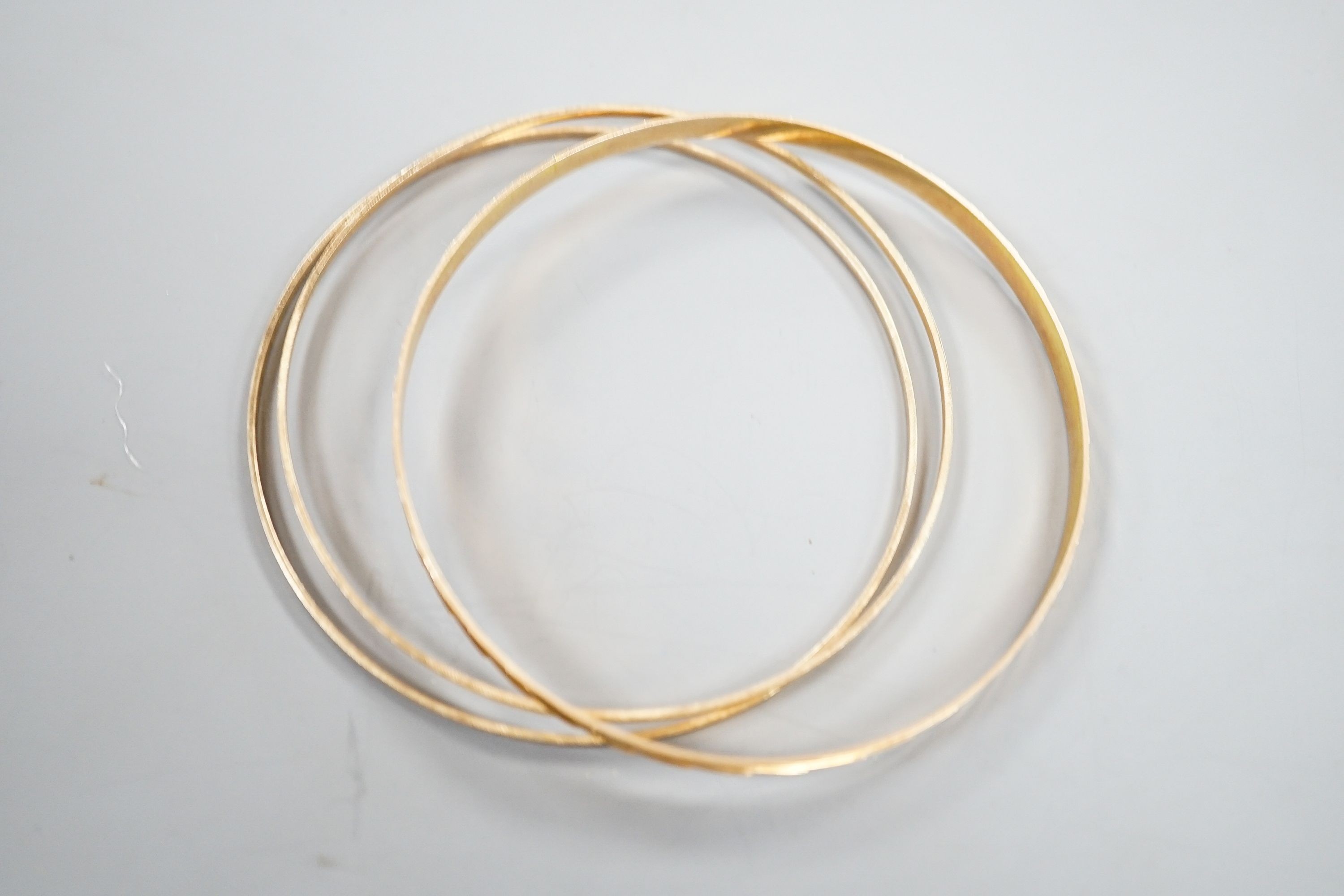 A 14k yellow metal bangle and two other brushed yellow metal bangles stamped 'K14', gross 12 grams.